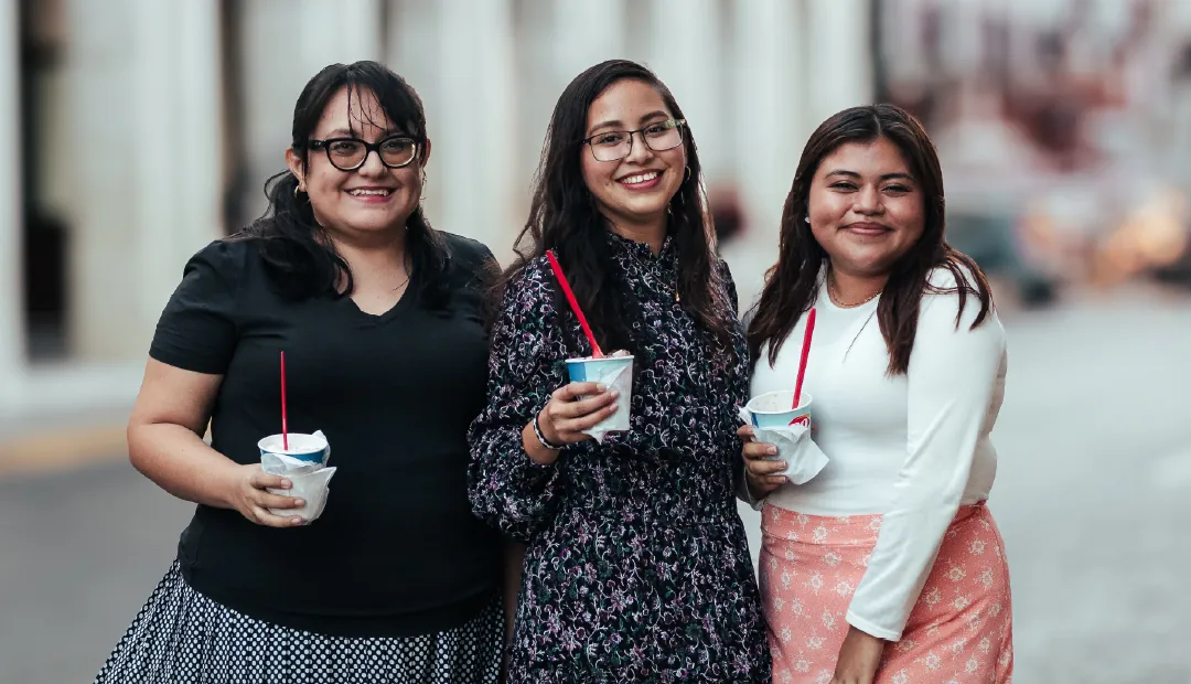 Tres mujeres latinas sonriendo juntas en la ciudad